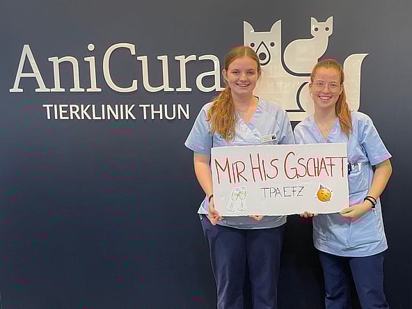 Zwei Frauen in Kitteln halten ein Schild.