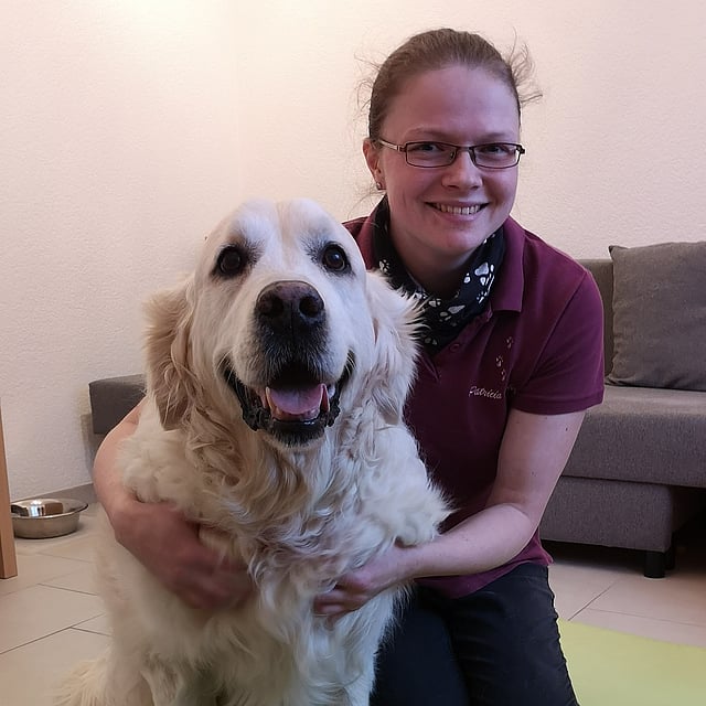 Eine Person, die mit einem Hund auf einer Matte sitzt.