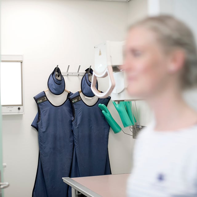 Eine Person in einem Raum mit blauen Kleidern an einer Wand.