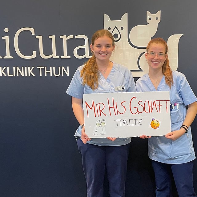 Zwei Frauen in Kitteln halten ein Schild.