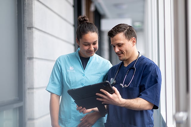 Eine Person und eine Person, die auf ein Tablet schaut.