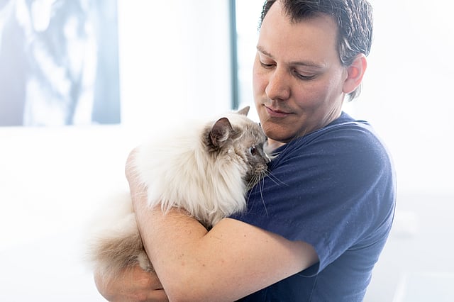 Un homme tient un chat dans ses bras